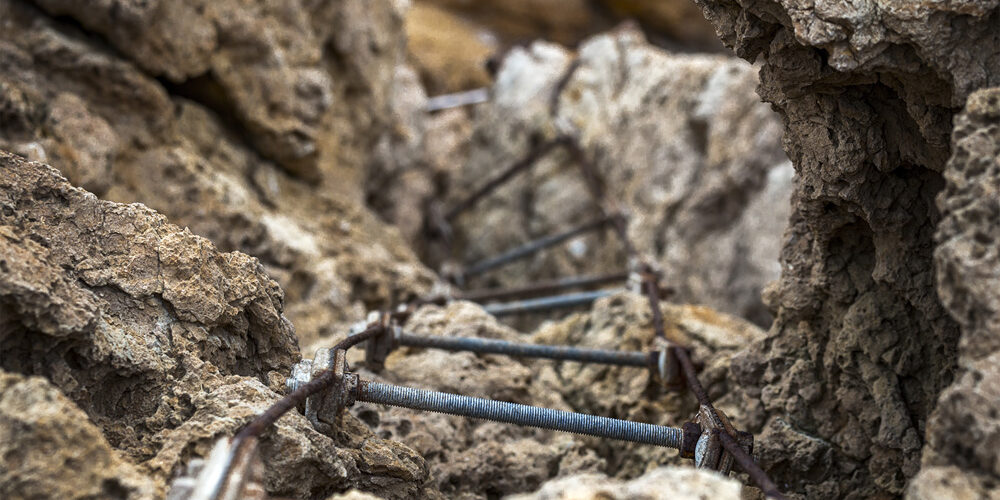 Detalle de una escalera oxidada entre rocas, mostrando las marcas del tiempo en este entorno natural.