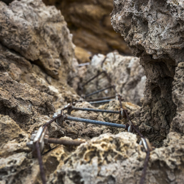 Detalle de una escalera oxidada entre rocas, mostrando las marcas del tiempo en este entorno natural.