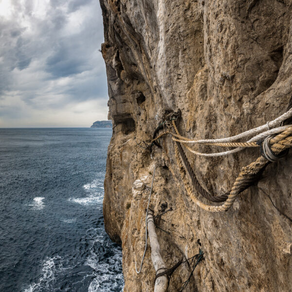 Vista de cuerdas y maderas usadas como soporte en un acantilado frente al mar, resaltando las técnicas tradicionales de los pescadores.