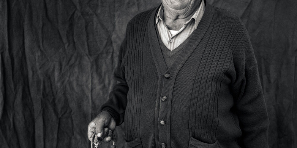 Retrato en blanco y negro de un hombre mayor sosteniendo herramientas de pesca.