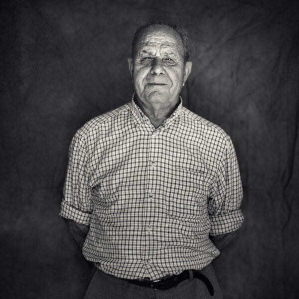 Retrato en blanco y negro de un hombre mayor con camisa a cuadros y expresión serena.